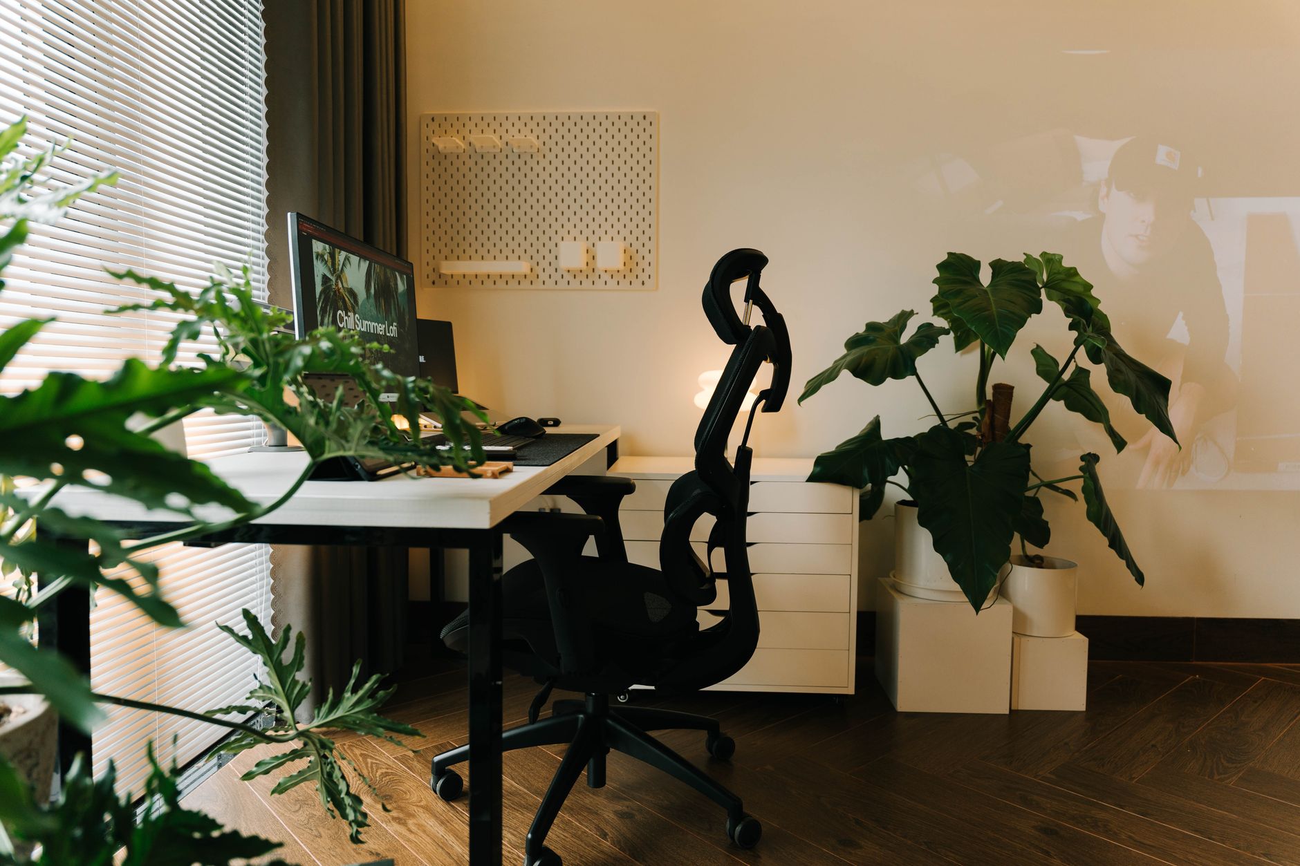 Stilfuldt hjemmekontor med planter og ergonomisk stol, indrettet til produktivt arbejde.